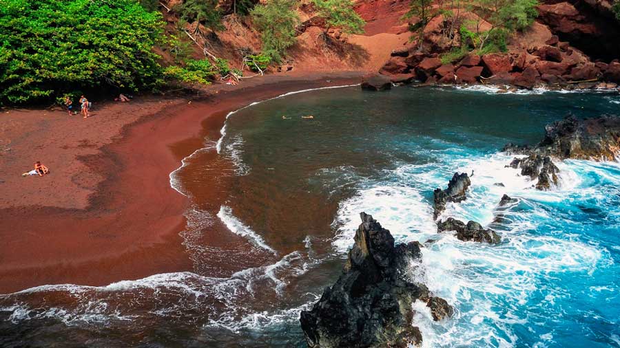 Aerial view of waves from Kaihalulu Beach coming at the red sands