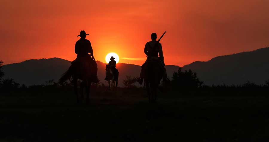 Silhouette of cowboys during sunset