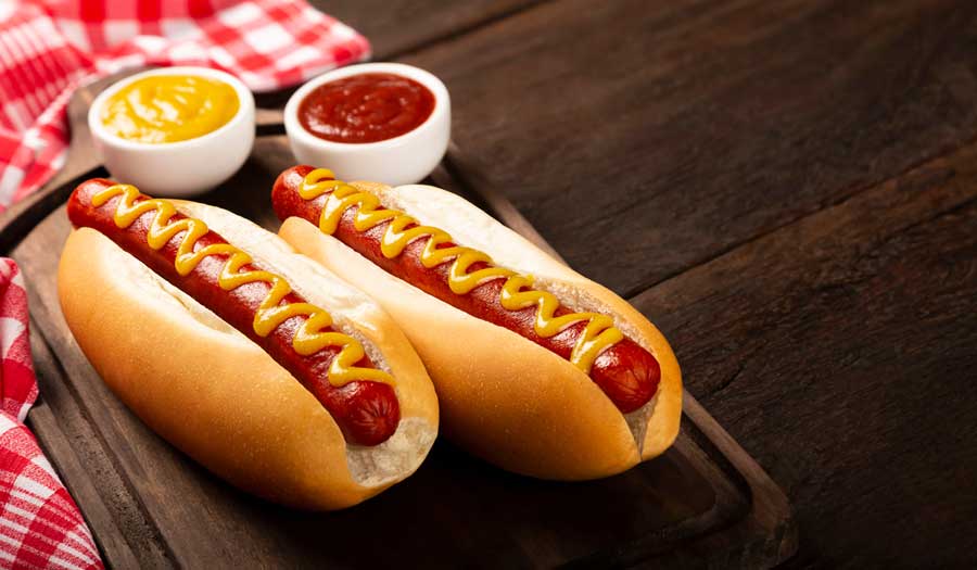Hot dogs on wooden board with ketchup and mustard